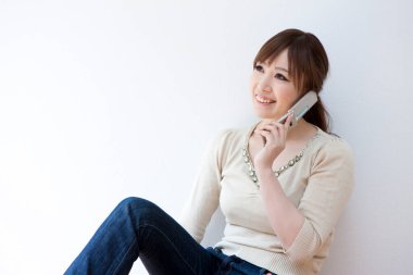 Genç bir kadın yerde cep telefonuyla konuşuyor.