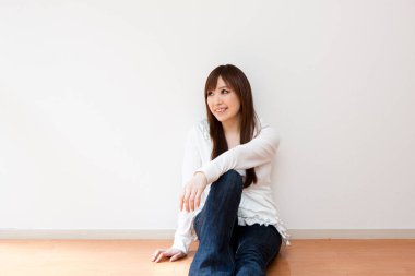 Japon kadın boş odada yerde oturuyor.
