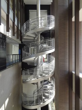 Modern spiral merdiven, uzun cam bina iç mekanında dönüyor.