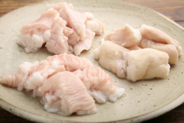 Mutfak ortamında seramik tabakta sergilenen çeşitli et parçaları.