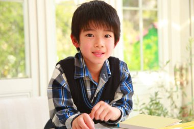 Küçük Asyalı çocuk evde resim çiziyor.