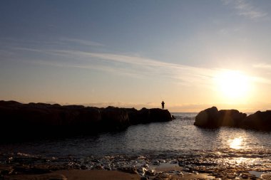 Okyanusun üzerinde dramatik bulutlarla portakal rengi günbatımı