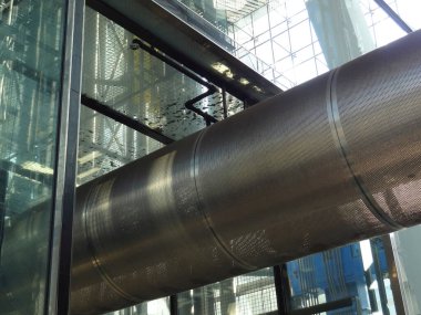 Modern mimari tasarım cam bir yapı içinde parlak metalik borular içeriyor, endüstriyel estetik ve yenilikleri vurguluyor