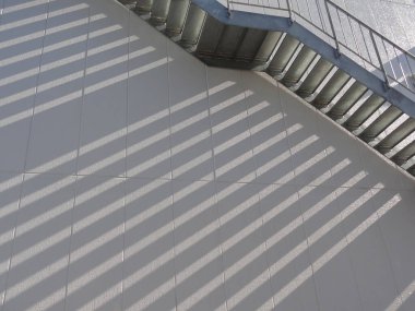 Çapraz çizgiler gri beton yüzeyde gölgeler oluşturuyor