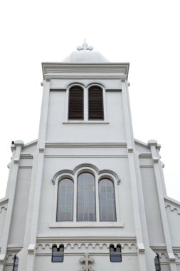 Belirgin mimari özelliklere sahip beyaz tarihi kilise binası bulutlu gökyüzünün altında sessiz bir muhitte yer alıyor.