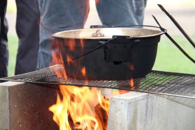 Ateşin üstünde yemek pişiren kişinin yakın plan görüntüsü.        