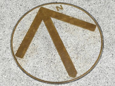 Metal pusula kaldırım yüzeyinde kuzeye doğru işaret ediyor.