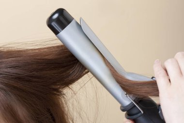 Açık arkaplanda saç yapan bir kadının kırpılmış görüntüsü.