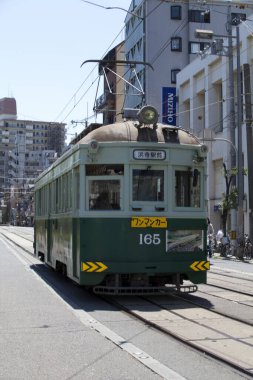 Şehir yolunda hareket eden yeşil tramvay 