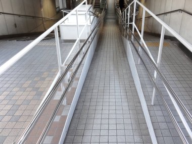 Rampa metal parmaklıklar ve döşeme döşemeleri ile aşağı iniyor.