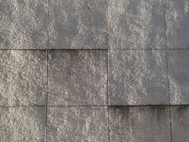 Üst üste binen panelleri olan gri desenli duvar şehir mimarisinde modern bir estetik oluşturuyor.