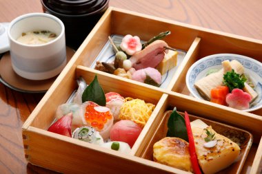 Lezzetli geleneksel Japon mutfağı sakin bir yemek deneyimi sırasında ahşap bir bento kutusunda servis edilir.