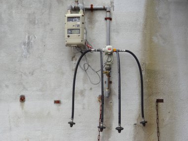 Eski elektrik sayacı yıpranmış beton duvara bağlı.