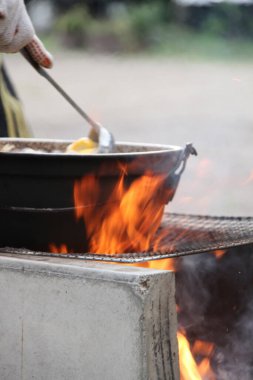 Ateşin üstünde yemek pişiren kişinin yakın plan görüntüsü.        