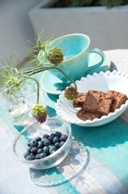 Taze böğürtlen ve kek, fincanda bardak ve masada çiçekler.   