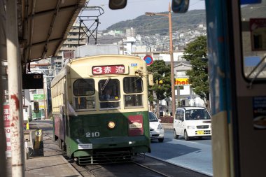 Tramvay ticari Japon caddesinde ilerlerken gün ışığı renkli arabayı aydınlatıyor..