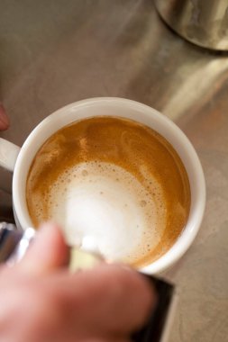 Kahveci sütlü kapuçino hazırlıyor.