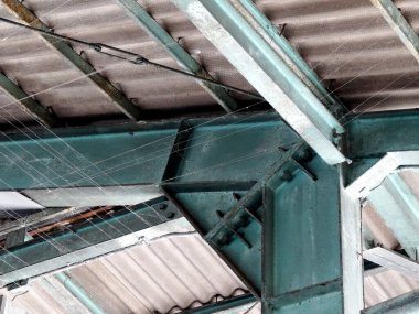 Endüstriyel çelik kirişler, kıvrımlı metal çatı yapısını destekliyor.