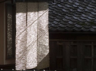 Güneş ışığı, dışarıda örülmüş bambu perdelerin arasından gölgeler salıyor.