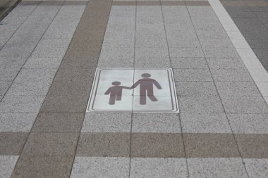 Yaya kaldırım tabelası yetişkin çocuğun elini tuttuğunu gösteriyor.