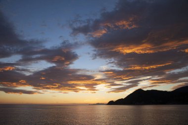 Gün batımında gökyüzü ve bulutların arasında güneş olan sakin bir deniz. Meditasyon okyanusu ve gökyüzü arka planı. Huzurlu deniz manzarası 