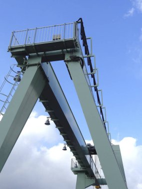 Büyük endüstriyel vinç parlak mavi gökyüzüne doğru yükseliyor.