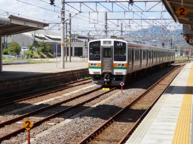 Tren, öğleden sonra güneşinde iyi korunan Japon demiryollarını gezer..