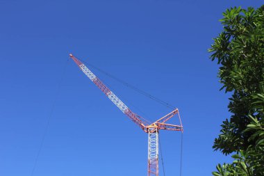 Mavi gökyüzünün arka planında inşaat alanı vincinin düşük açılı görüntüsü              