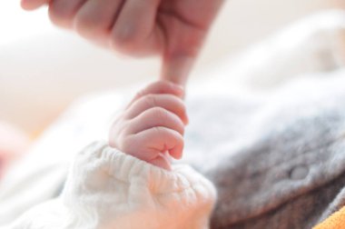 Yeni doğmuş bebek eli, annesinin parmağını tutuyor.
