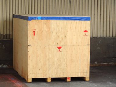 Endüstriyel depo duvarında duran büyük ahşap nakliye sandığı.