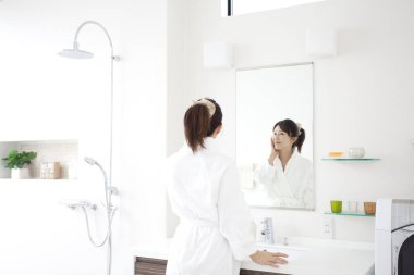 Genç, güzel Asyalı kadın banyoda günlük bakım rutinini yapıyor.