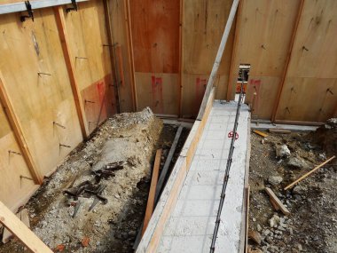 Ahşap duvarlar ve beton temeli gösteren inşaat alanı