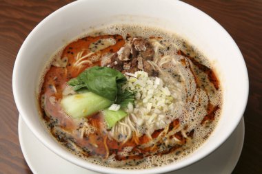 Sıcak bir restoranda servis edilen lezzetli çorba ve taze malzemelerle dolu bir kase ramen.