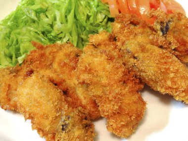 Kızarmış istiridye ve yanında doğranmış marul ve domates.