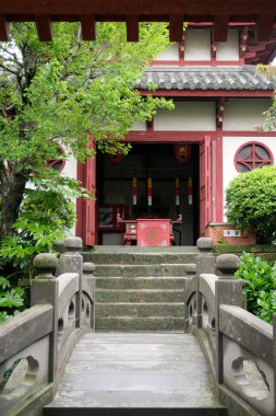 Çevresi yeşilliklerle çevrili geleneksel binaya giden taş basamaklar.