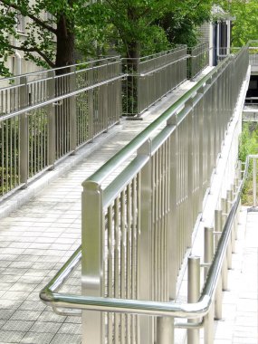 Modern bina girişine giden parlak metal tekerlekli sandalye rampası.