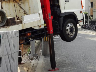 Büyük beyaz kamyon yerden kırmızı hidrolik dengeleyici kullanarak kalkıyor.