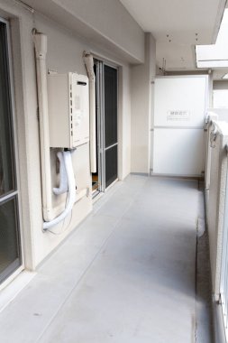 Araç gereçleri ve beyaz korkuluklardan oluşan dar bir apartman balkonu.