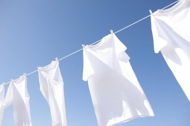Temiz beyaz elbiseler mavi gökyüzüne karşı kuruyor.