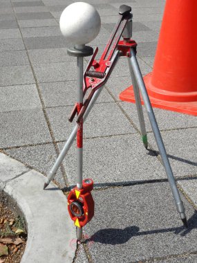 Turuncu koninin yanında prizma topu tutan tripodlar inceleniyor.