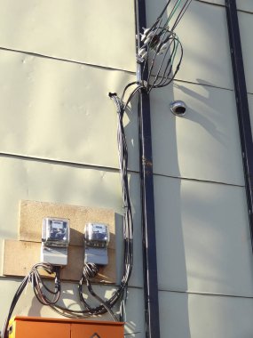 Şehir merkezinde gündüz vakti bina duvarına bağlı elektrik sayaçları ve kablolar
