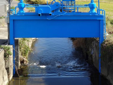 Dar beton su kanalları boyunca uzanan büyük mavi su kapağı.