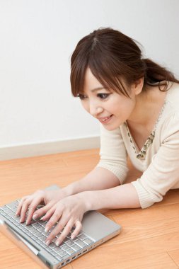 Evde dizüstü bilgisayar kullanan Japon kadın.