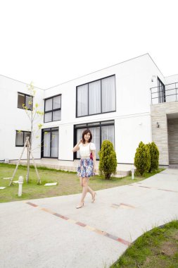 Asyalı güzel bir kadın binanın önünde yürüyor. 