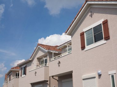 Mavi gökyüzüne karşı kırmızı çatıları olan modern banliyö evleri