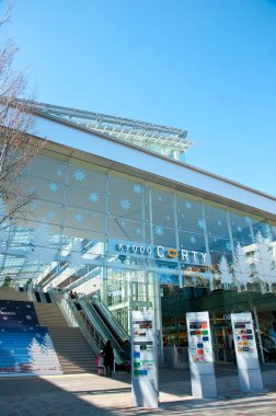 Yürüyen merdivenler ve mavi gökyüzü yansımalarının yer aldığı modern cam bina girişi