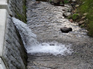 Taş duvarın yanındaki taş duvardan akan bir dere.