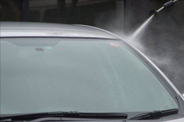 Yüksek basınçlı su hortumuyla yıkanan bir araba.