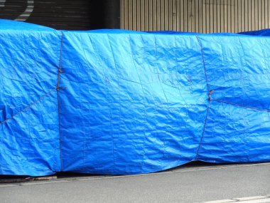 Kentsel cadde boyunca nesneleri kaplayan büyük mavi branda