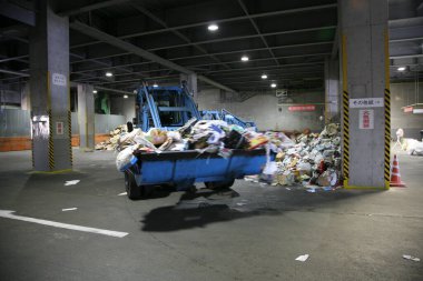 Arkasında çöp yığını olan mavi bir kamyon.